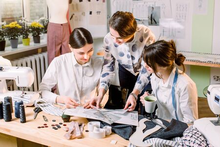 Three attractive young fashion designers carefully creating new fashionable styles of pants. Dressmakers making clothes. Fashion, dressmaker, sewing conceptの写真素材