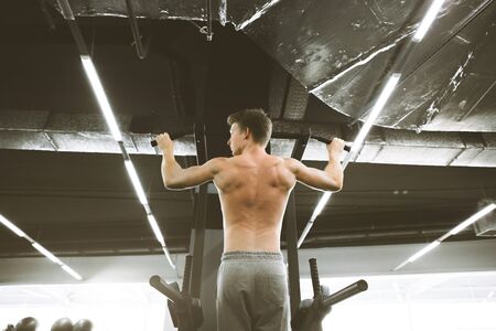 Good looking athletic man concentrating for his pull up workout at the gym.の写真素材