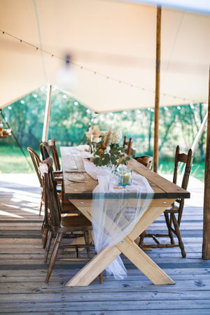 Wedding or dinner reception table, decorated in rustic style, outdoors in stylish tent. Reception on open air, rustic wedding.の写真素材