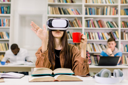 Young smart confident woman in casual clothes sitting in library and experiencing new device VR...