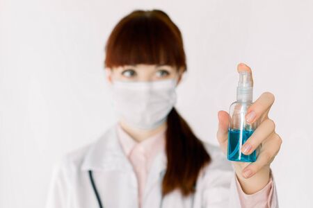 Young female doctor or nurse holds an antiseptic gel in hands, shows a sanitizer to camera. Antiseptic, hands hygiene and healthcare concept. Covid-19, infections prevention. Focus on hand with gelの写真素材