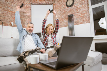 Emotional caucasian family sitting on couch with hands up while celebrating victory during video...
