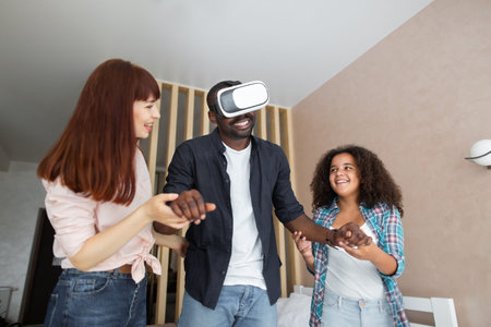 New reality. Joyful emotional pleasant black man holding hands of his wife and daughter, while...