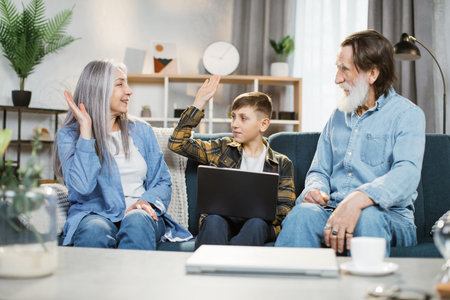 Happy family, Cheerful senior couple sitting on the sofa with young grandson in the living room,...