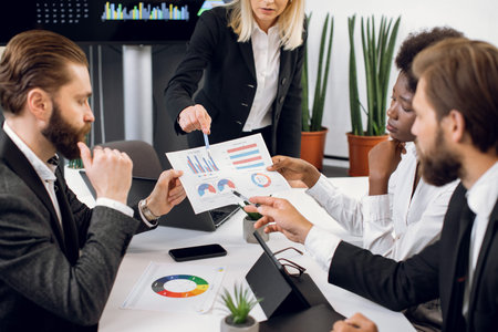 Cropped image of attractive confident blond businesswoman, pointing on the financial report with...