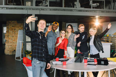 Positive group of business people making selfie in modern office. Group of six hipster workers making selfie after meeting.の写真素材