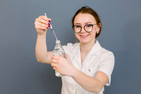 beautiful woman doctor cosmetologist holding syringe and bootle with solution for beauty injections. isolated female studio portrait.の写真素材