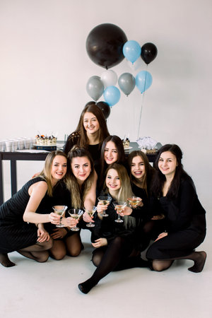 Beautiful girls in black celebrating birthday sitting on the floor. Decorated table with air...