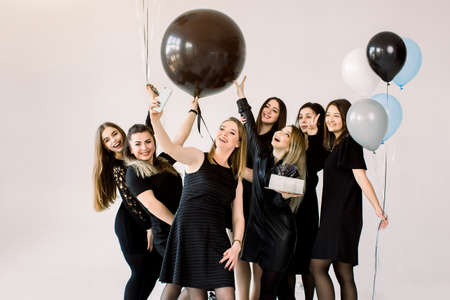 Group of seven girls best friends making selfie on smartphone, enjoying birthday party with cake and air balloons, having fun, smiling and laughing. Friendship and birthday party concept.の写真素材