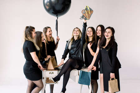 Business team of sexy attractive women celebrating female colleagues birthday in studio. Friends meeting, Birthday celebration of a pretty girl, who received a fashionable handbag as presentの写真素材