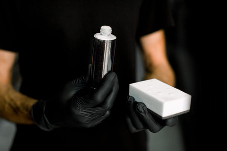 Car detailing, professional auto care products. Cropped image of male hands in protective gloves,...