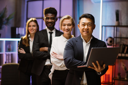 Happy multiethnic coworkers standing in a row in creative office, posing on camera with arms...