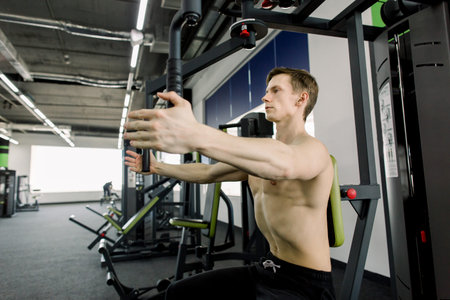Young man training in the gym. Ripped bodybuilder working out in gym.