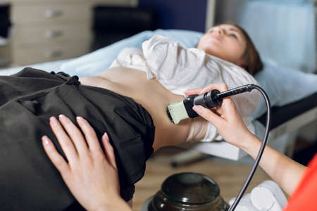 Extracorporeal shockwave therapy in urology. Cropped shot of lying woman patient, having ultrasound to determine kidney stones position before the lithotripsy procedureの写真素材