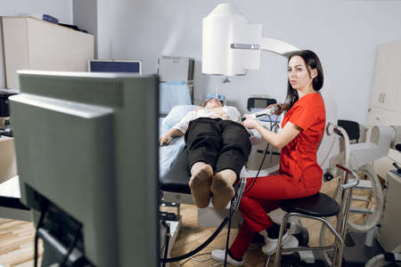 Extracorporeal shock wave therapy. Kidney stone treatment. Front view of woman doctor looking at the digital screen of the lithotriptor to determine stones position of woman patient.の写真素材