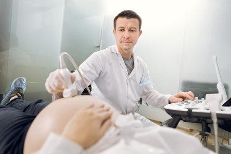 Close up portrait of man doctor using ultrasound to check fetal health of his patient, young...