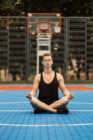 Muscular man sitting in lotus yoga position. Yoga instructor with muscular body stretching. Sport and health care. Coach demonstrate yoga asana outdoors. Flexible body is his merit.の写真素材