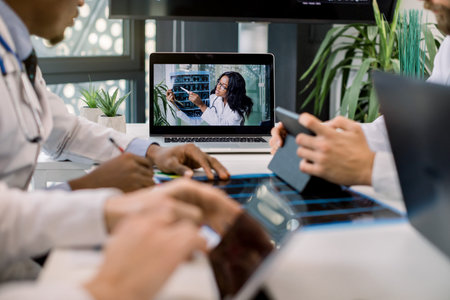 Cropped image of multiracial doctors using laptop for video conference with African female...