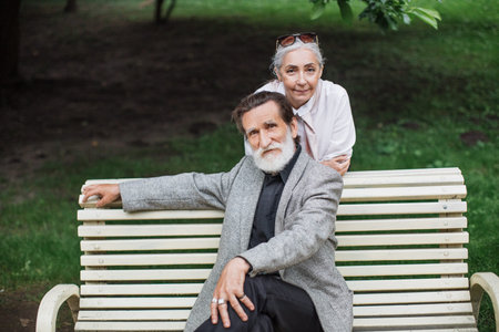 Attractive caucasian pensioners dressed in elegant clothes relaxing at park during free time. Happy...
