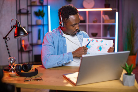 Remote work and freelance concept. Young confident skilled African man in headphones, holding online...