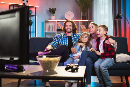 Happy smiling friendly family, mother, father, son and daughter, sitting on the sofa at home in the...