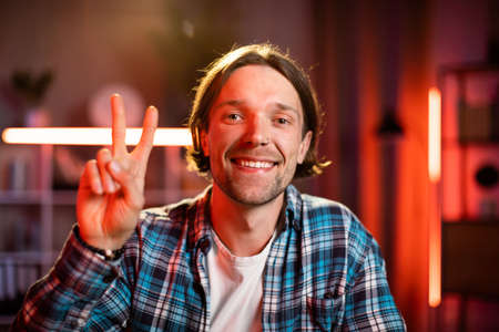 Attractive man sitting at desk with hands crossed on the chest and looking at camera. Caucasian male in casual wear taking break during process hours at home.の写真素材