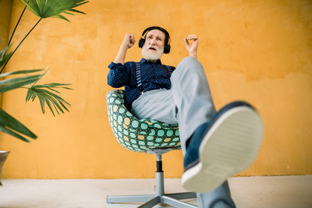 Full length portrait of handsome elderly bearded man, wearing stylish hipster clothes, relaxing in...