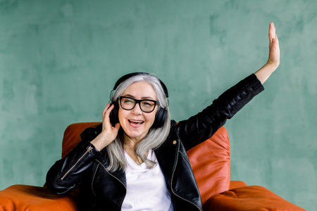 Happy positive pretty senior woman, dressed in stylish leather jacket, which enjoying favourite...