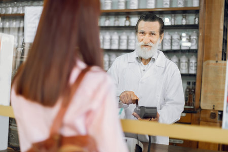 Back view of young Caucasian woman customer, paying for pills with credit card in old vintage...