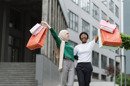 City shopping concept. Outdoor urban lifestyle portrait of two diverse young women, African and...