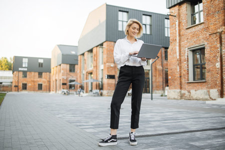 Business woman in white shirt working on laptop. Professional businesswoman using digital device...