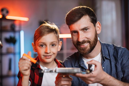 Portrait of smiling father with lovely son holding display card in hands after successful repairing....