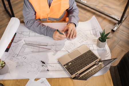 Close up of hands of senior architect, engineer or designer sitting at table and analysing...