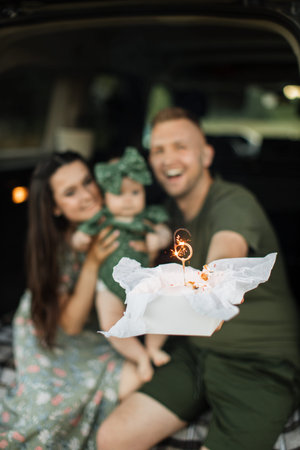 Focus on delicious cake with number six. Portrait of a happy family, mom, dad and little girl...