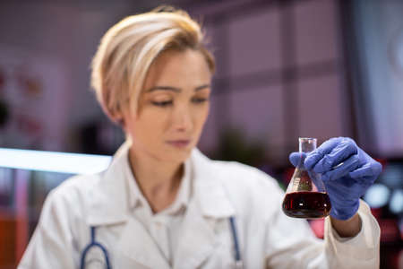 Modern medical research laboratory: female scientist working with flask, analysing biochemicals samples. Advanced scientific lab for medicine, microbiology developmentの写真素材