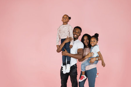 Time with family. Overjoyed african american family laughing and posing isolated over pink studio...