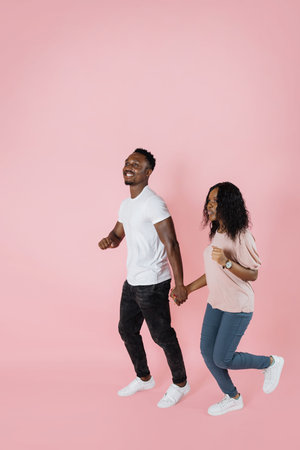 Full length shot of a african american man and woman in casual outfit walking or running together...