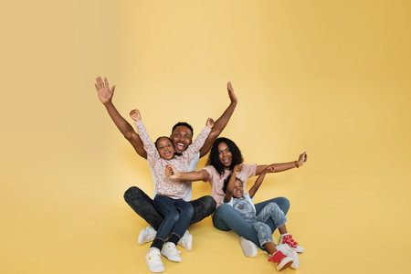 Family fun. Young african american parents spending time with their little daughters with open arms,...
