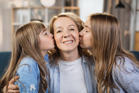 Mothers Day. Caucasian mother holds her two children, daughters while they hug and kiss her. Happy...