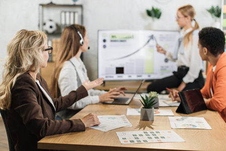 Group of competent diverse female economists discussing business ideas while gathering at office...