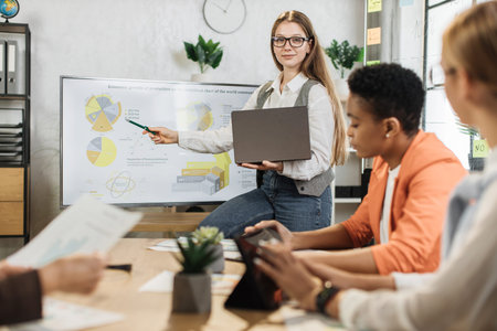 Caucasian woman presenting financial report on monitor for multiracial female colleagues at modern...