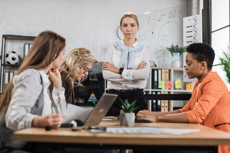 Multi ethnic company workers sitting at desk with modern devices, preparing financial report and listening speech of their young female boss. Concept of technology and cooperation.の写真素材