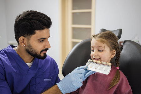 Confident dentist checking and selecting color of young caucasian girls teeth. Visual method of...