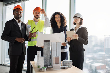 Group of four colleagues standing near building complex prototype project during successful...
