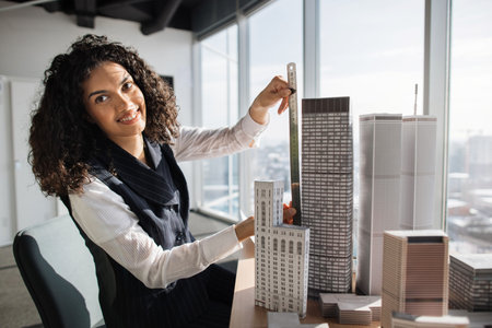 Curly female engineer working on building complex prototype project of residential or business...