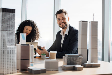 Diverse multi ethnic team of executive directors with young bearded male boss, on a meeting in conference room, sharing opinions, working with papers, laptop 3d city modelの写真素材