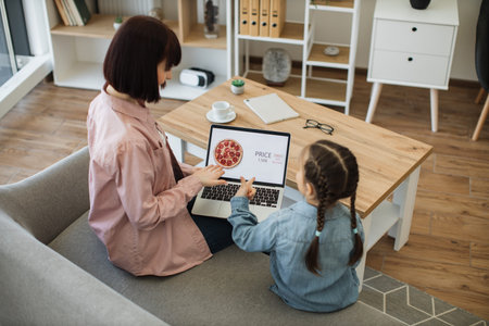 Happy mother and cute little daughter purchasing tasty pizza with discount of 65 percent using...