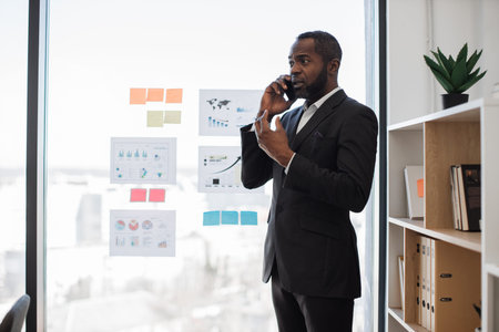 African american man in business suit making phone call using modern smartphone in comfortable...