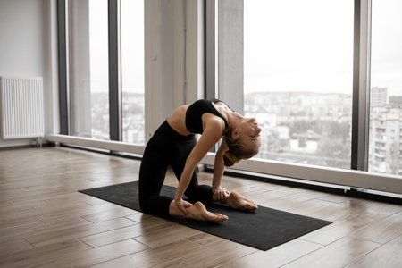 Athletic caucasian woman with bare feet standing in Camel Pose during training at fitness center....