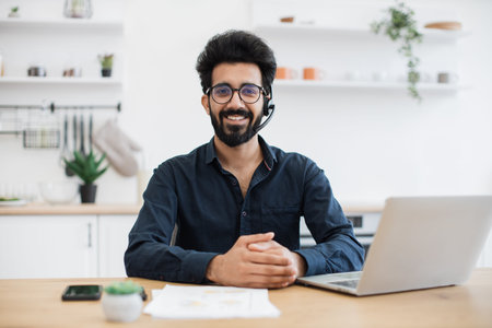 Portrait of smiling person wearing headset with microphone posing with documents and portable...